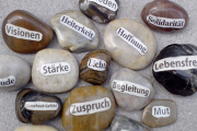 Das Bild zeigt Steine mit Aufschriften: Visionen, Heiterkeit, Stärke, Zuspruch, Begleitung, Mut, Lebensfreude, Solidarität 
